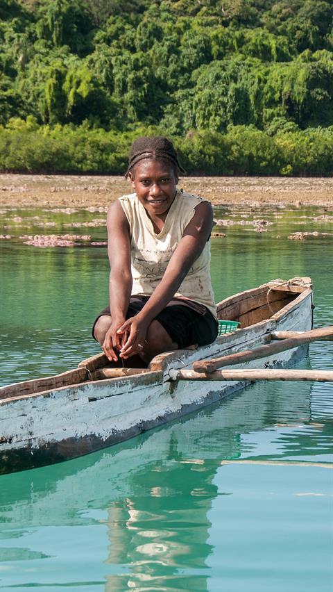 Schüchterne junge Frau beim Fischen mit ihrem Auslegerkanu. Gesehen in den nördlichen Inseln von Vanuatu.